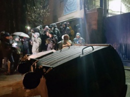 Протестующие несут к зданию суда мусорные баки и табуретки