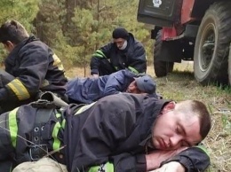 Спасатели, которые борются с огромными пожарами в Чернобыле, спят на земле во время перерыва. Фото